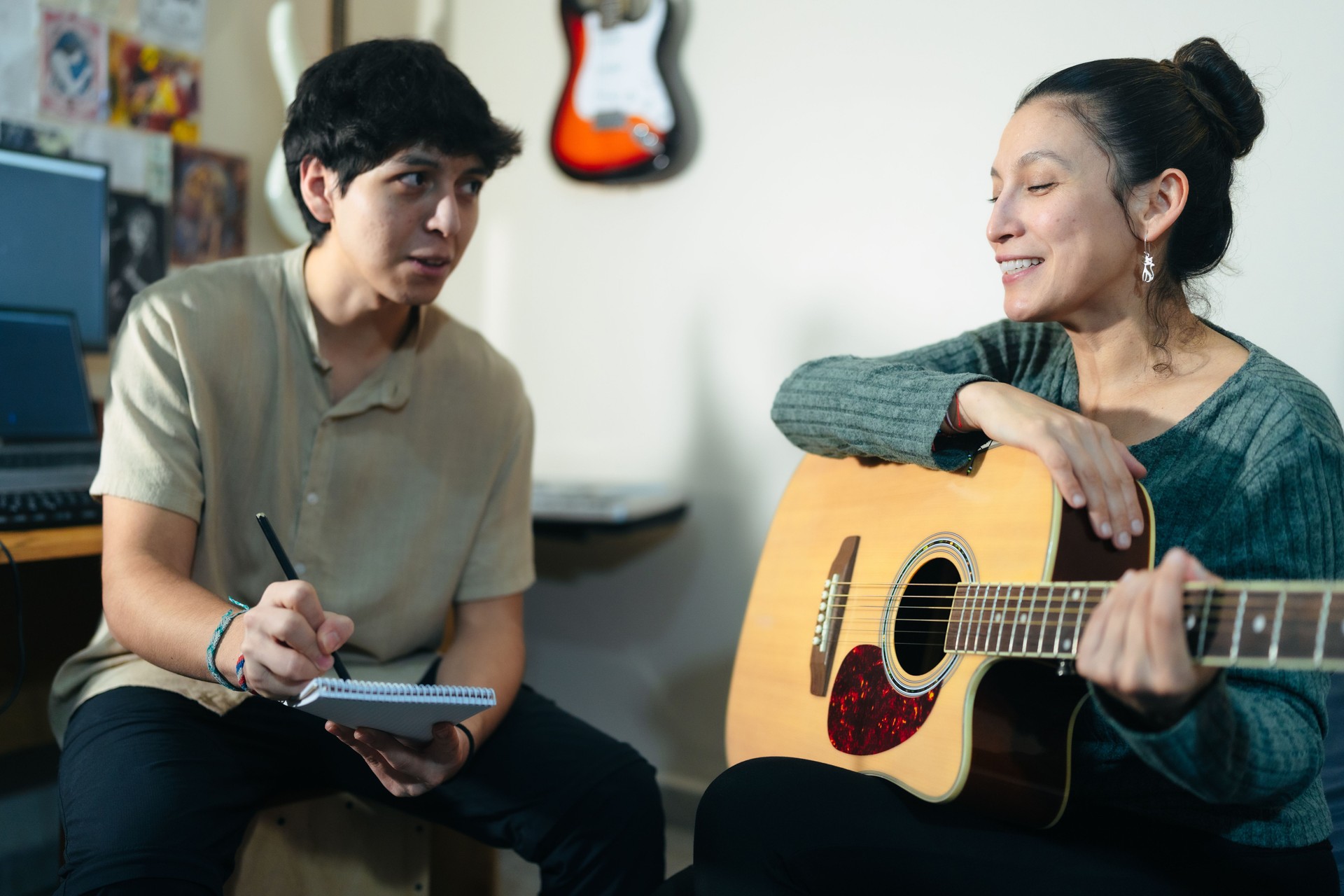 Music teacher playing acoustic guitar and giving lessons to student